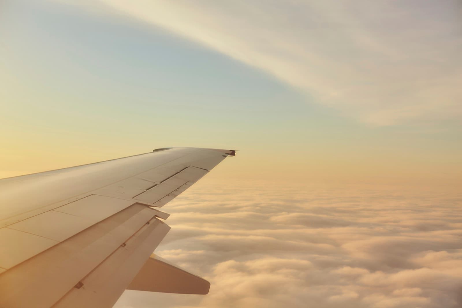 Ala de un avión sobre las nubes con luz cálida